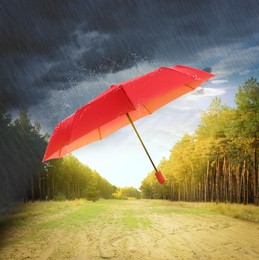 Open red umbrella under heavy rain in forest