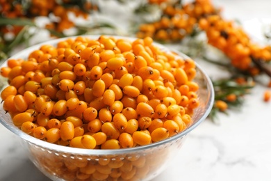 Ripe sea buckthorn berries on white marble table, closeup