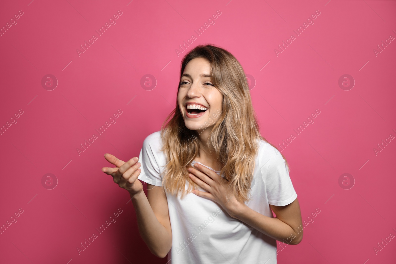 Photo of Cheerful young woman laughing on pink background