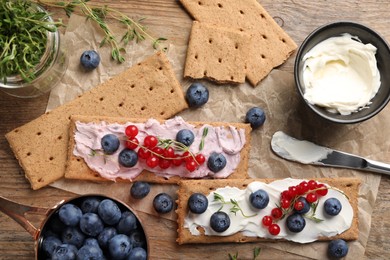 Tasty crispy crackers with cream cheese, thyme and berries, flat lay