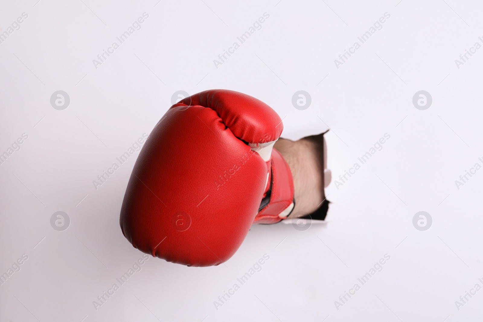 Photo of Man breaking through white paper with boxing glove, closeup