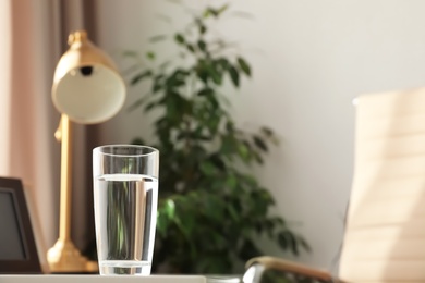 Glass of fresh water on table indoors. Space for text