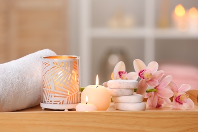 Photo of Composition with candles, flowers and stones on wooden table in spa salon. Space for text