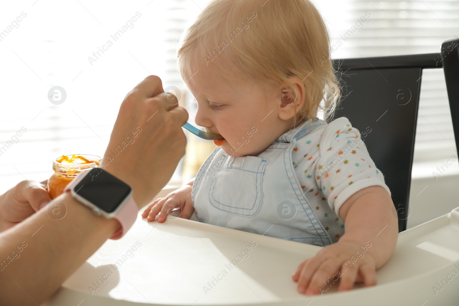 Photo of Mother feeding her cute little baby with healthy food at home