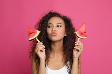 Photo of Beautiful young African American woman with pieces of watermelon on crimson background