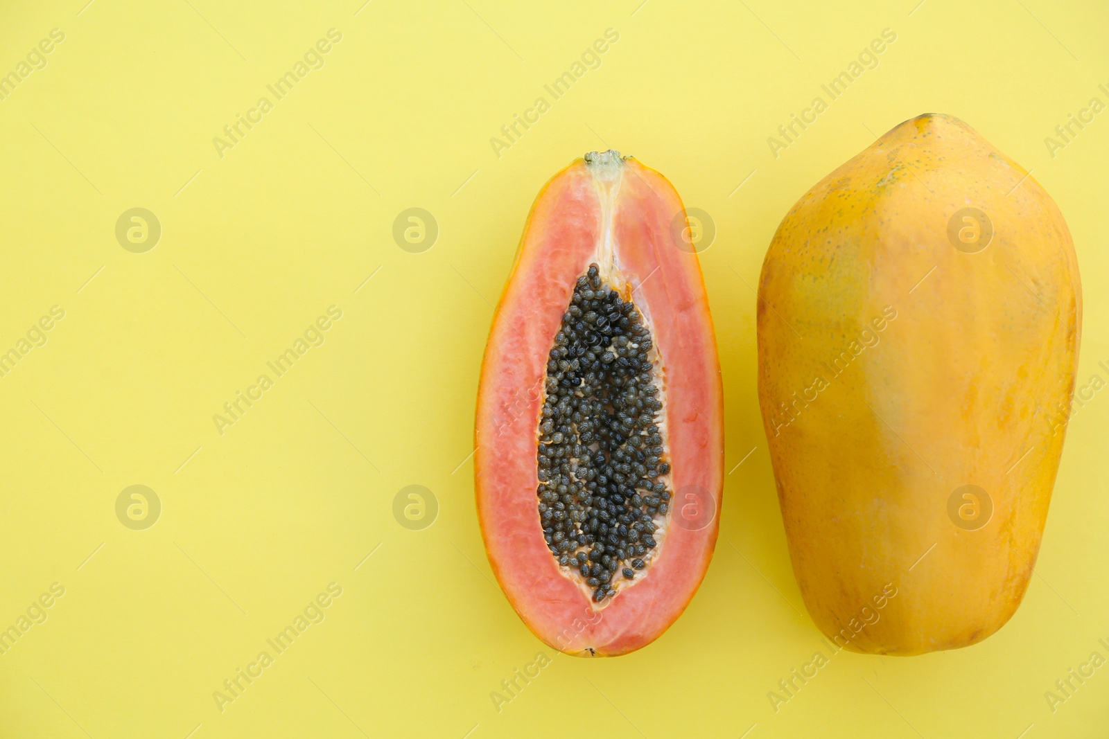 Photo of Fresh ripe cut and whole papaya fruits on light green background, flat lay. Space for text