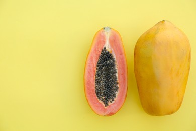 Photo of Fresh ripe cut and whole papaya fruits on light green background, flat lay. Space for text