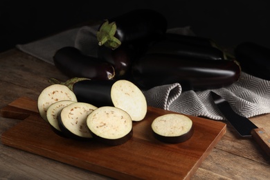 Cut and whole raw ripe eggplants on wooden table