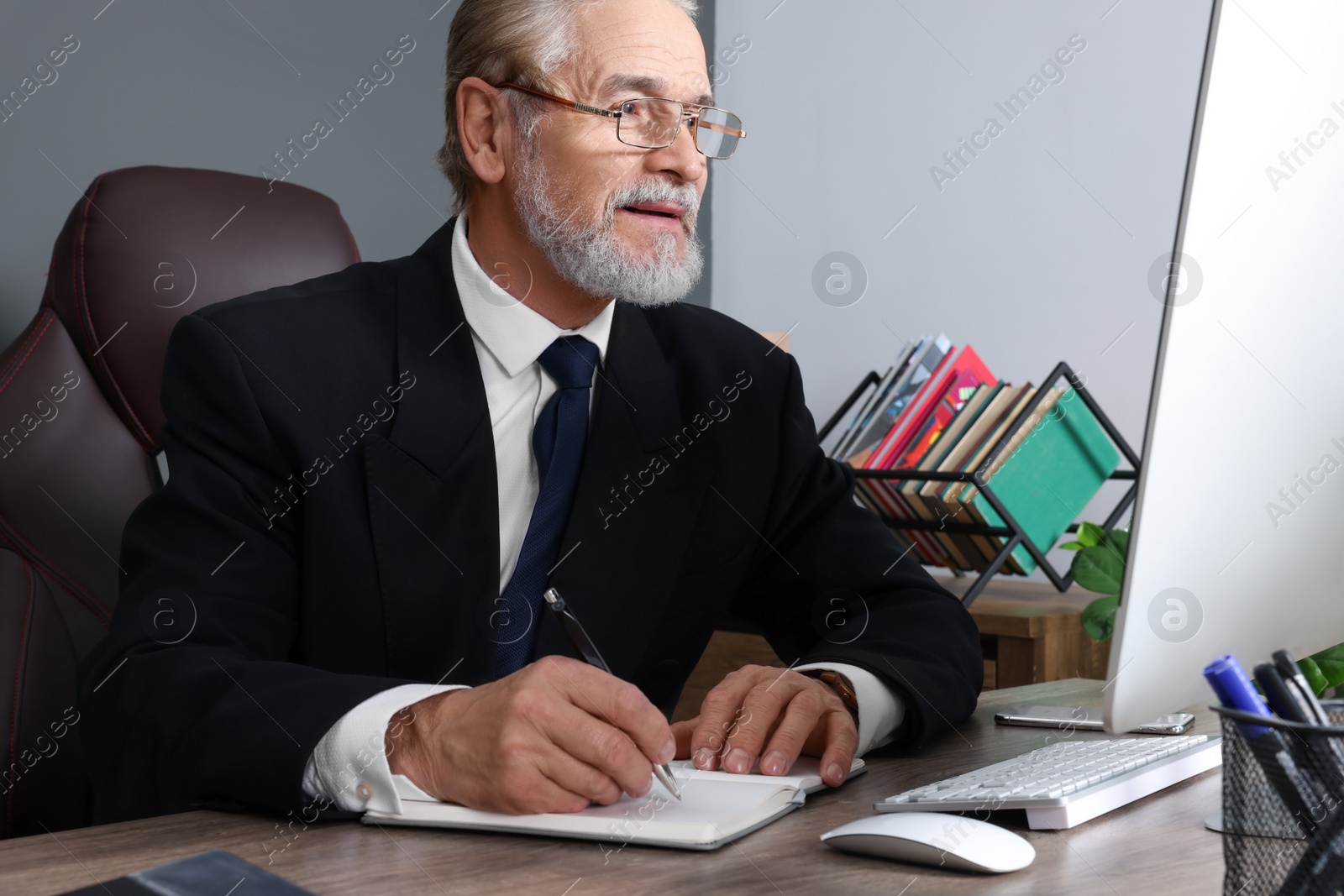 Photo of Senior boss working at wooden table in office