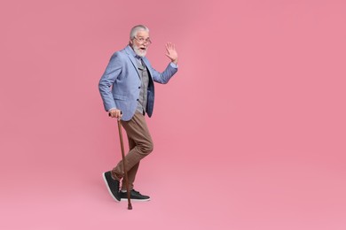 Photo of Senior man with walking cane on pink background