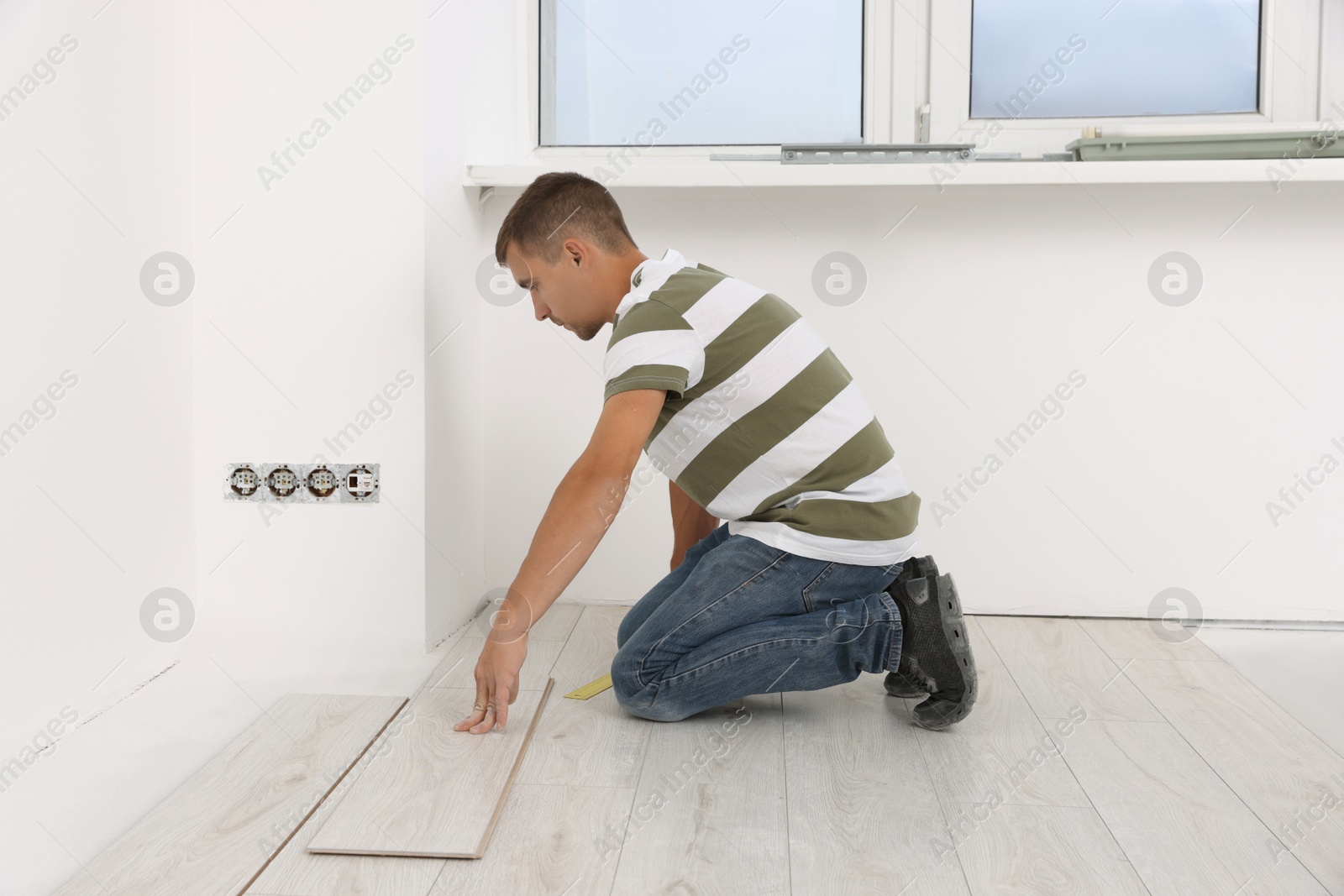 Photo of Professional worker installing new laminate flooring indoors