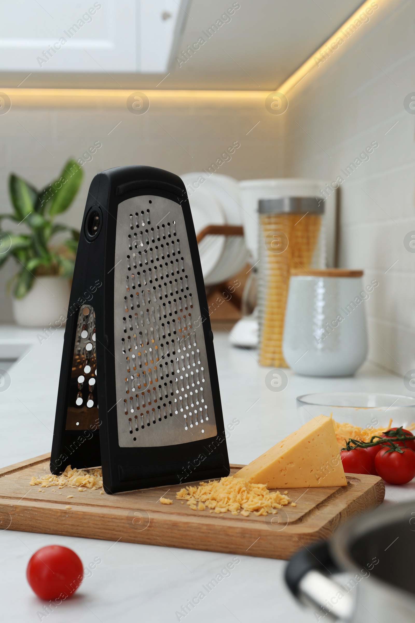 Photo of Grater, cheese and cherry tomatoes on kitchen counter