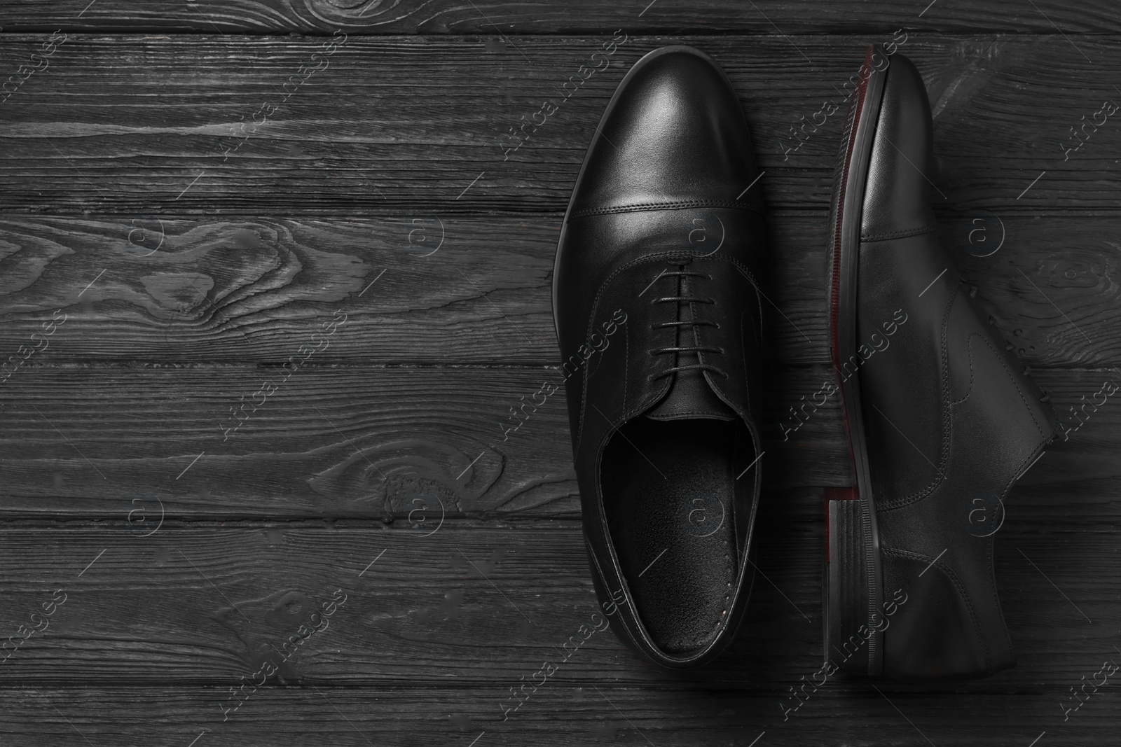 Photo of Pair of leather men shoes on black wooden background, top view. Space for text