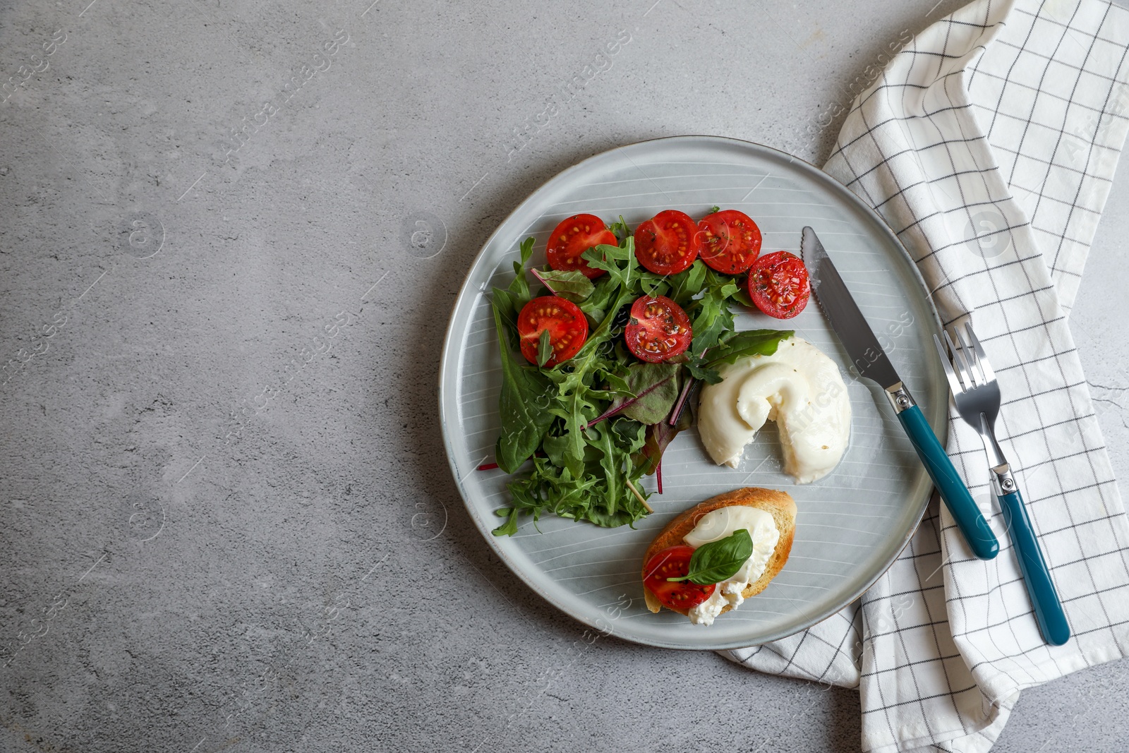 Photo of Delicious burrata cheese with tomatoes, arugula and toast served on grey table, top view. Space for text