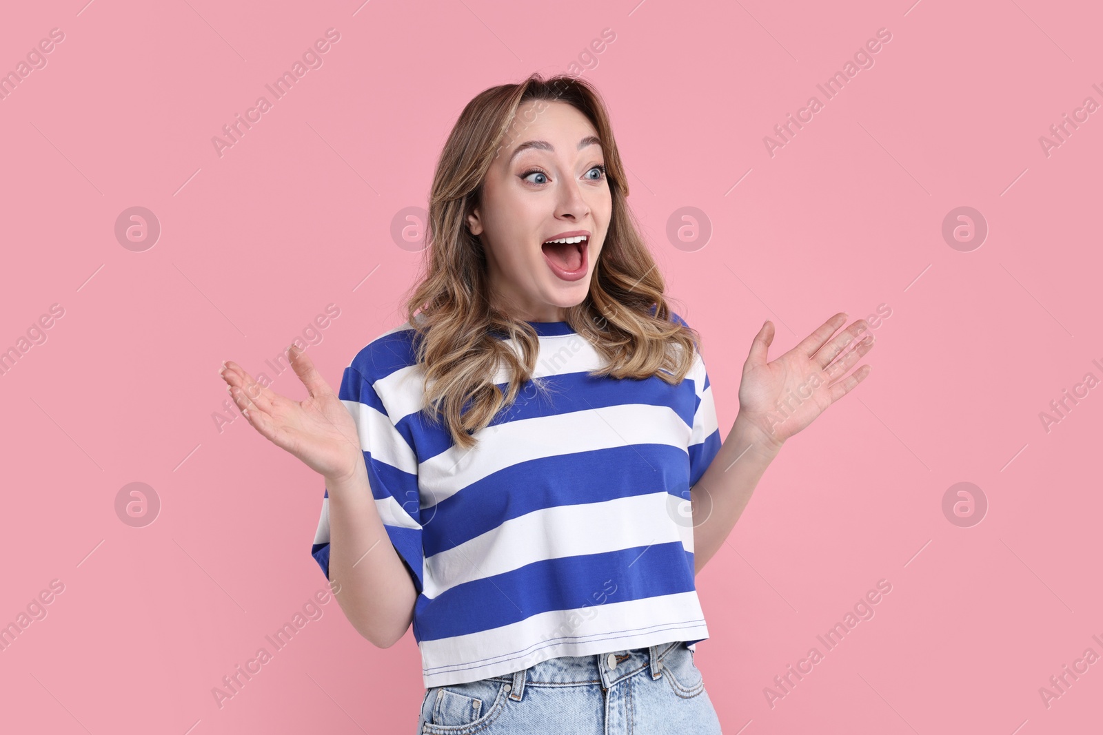 Photo of Portrait of happy surprised woman on pink background