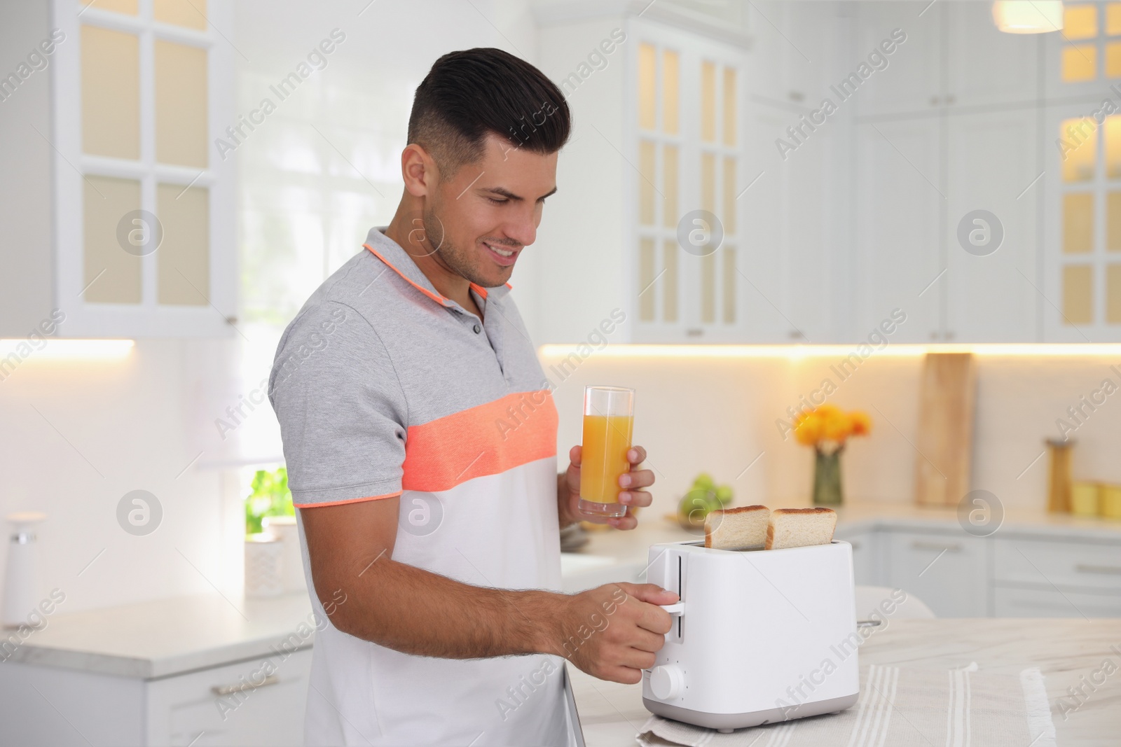 Photo of Man using toaster at table in kitchen