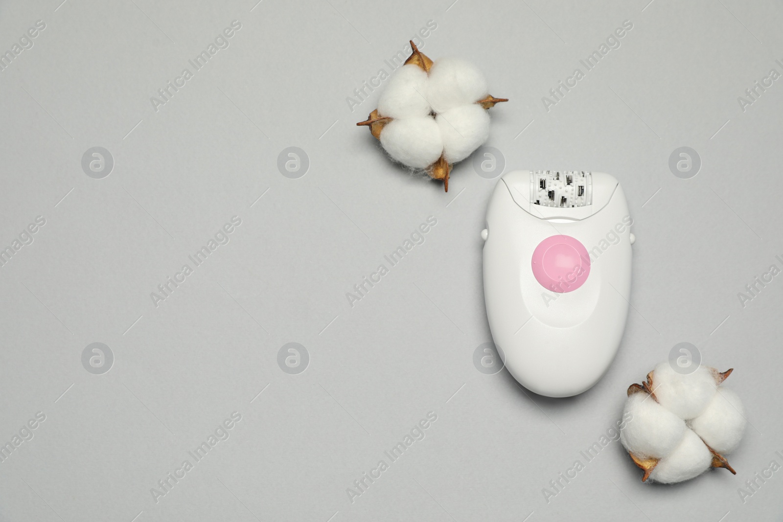 Photo of Modern epilator and fluffy cotton flowers on light grey background, flat lay. Space for text