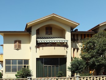 Exterior of residential building with green trees in yard on sunny day