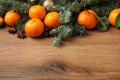 Photo of Christmas composition with tangerines on wooden background. Space for text