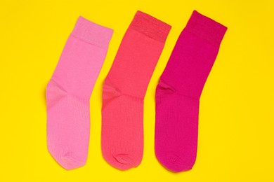 Photo of Different pink socks on yellow background, flat lay