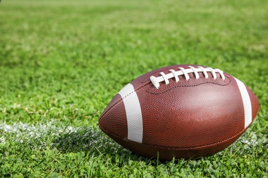 Photo of Ball for American football on fresh green field grass