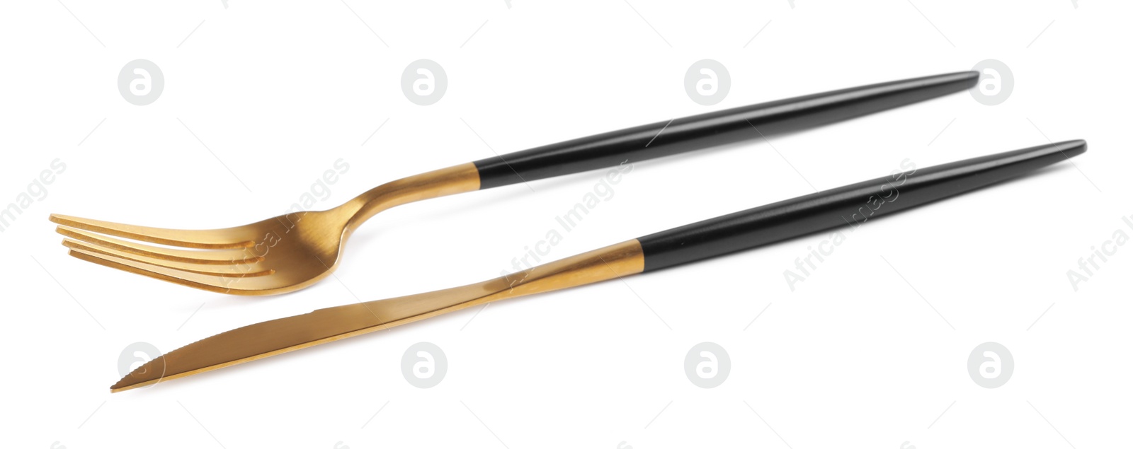 Photo of New golden fork and knife with black handles on white background