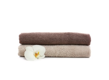 Photo of Clean folded towels with flower on white background