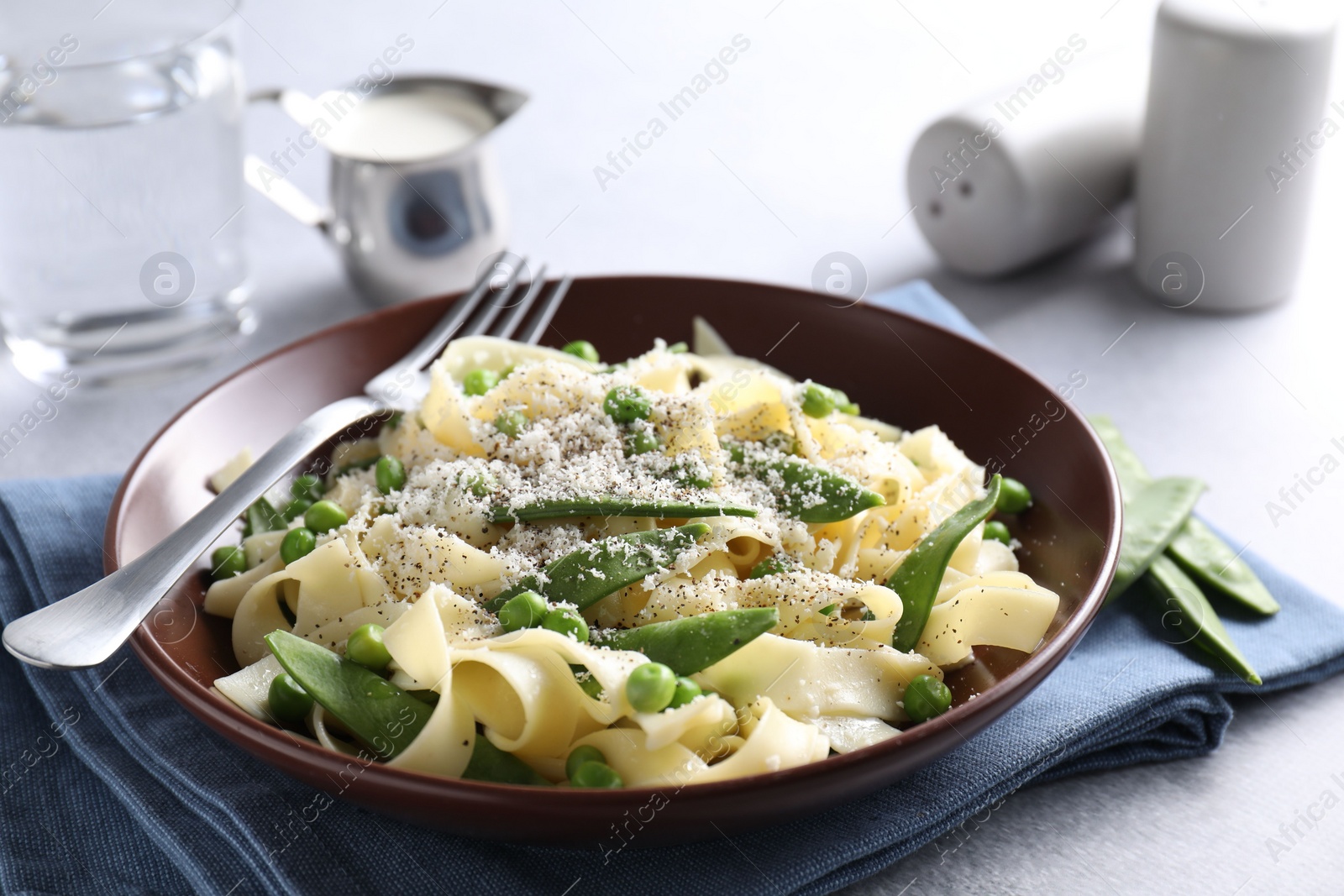 Photo of Delicious pasta with green peas and cheese served on grey table