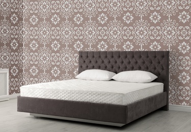 Large bed near patterned wallpapers. Interior design 