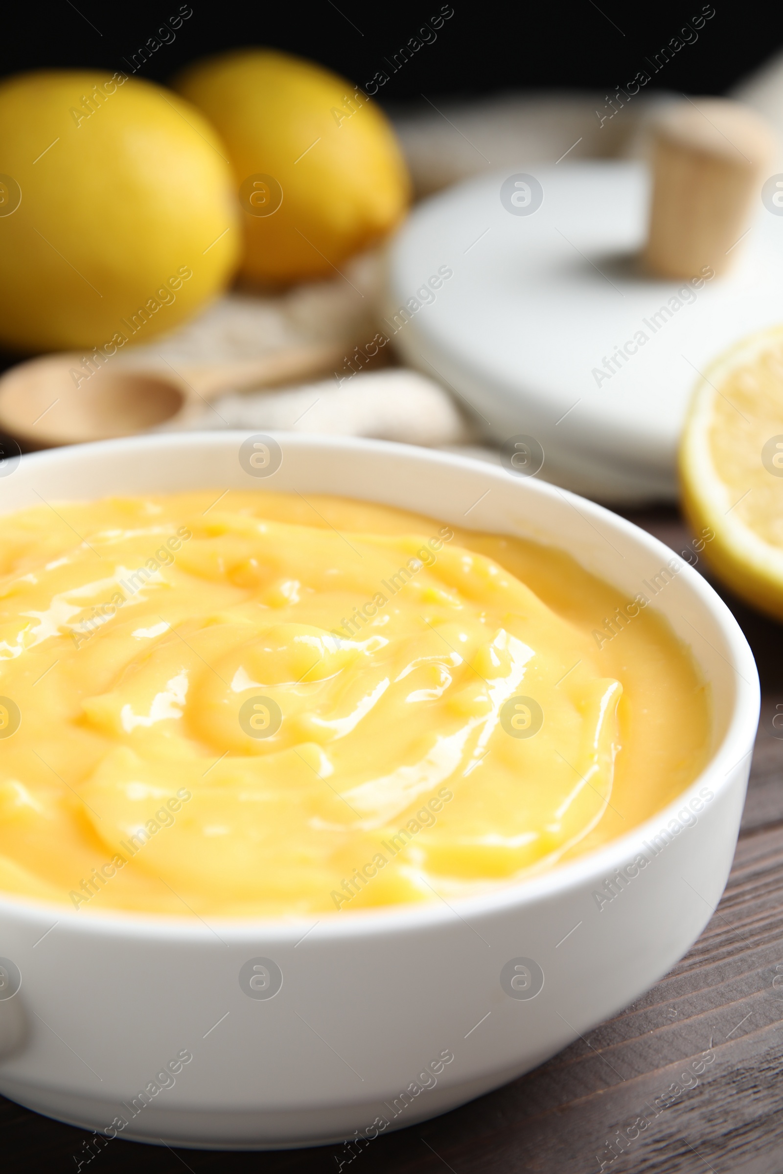 Photo of Delicious lemon curd in bowl on dark wooden table, closeup