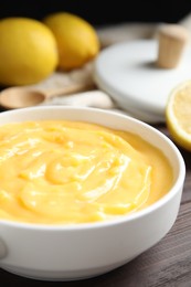 Photo of Delicious lemon curd in bowl on dark wooden table, closeup