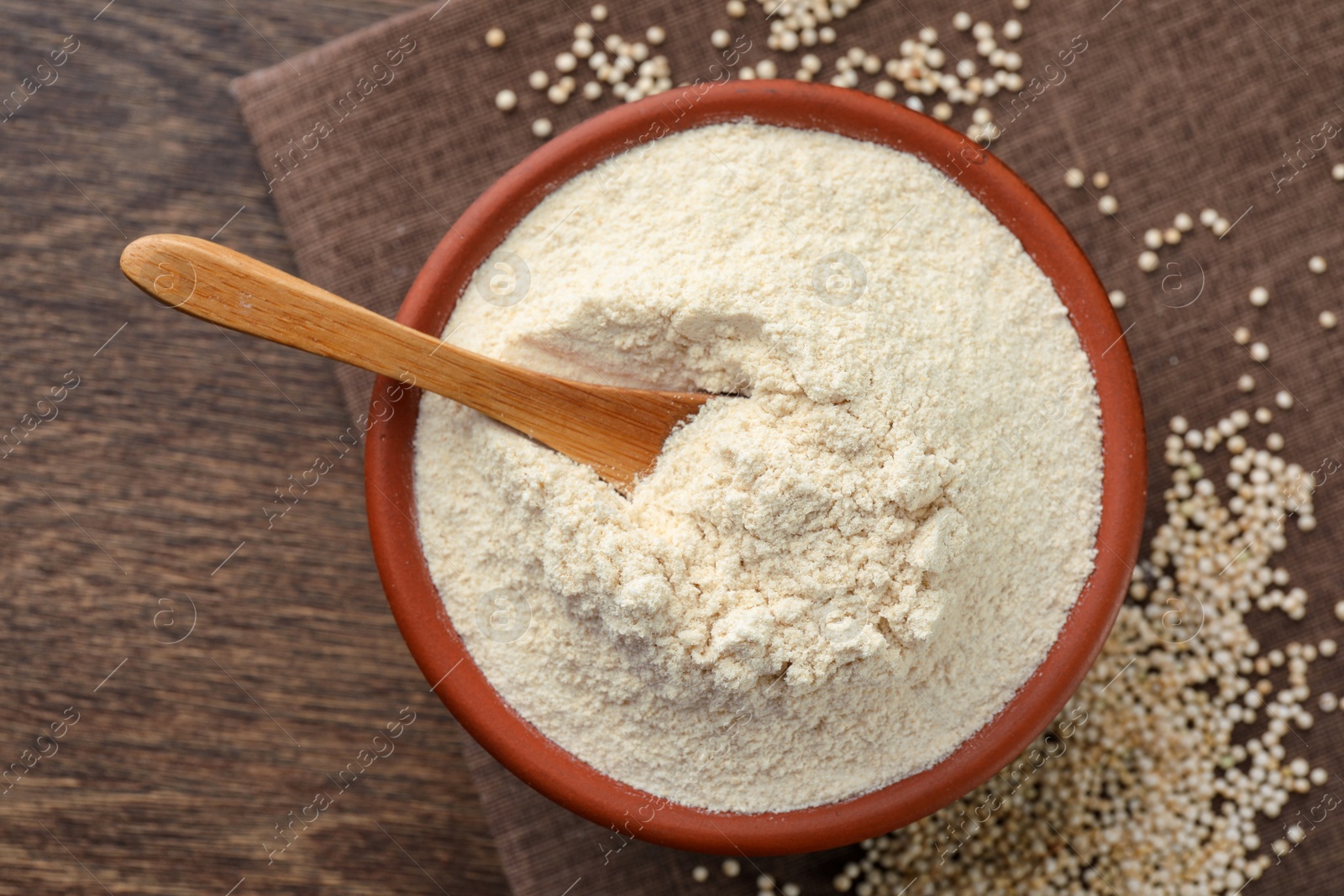 Photo of Quinoa flour in bowl and seeds on wooden table, top view