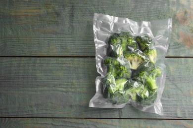 Photo of Vacuum pack of broccoli on wooden table, top view. Space for text