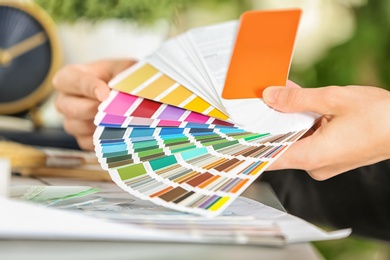 Photo of Female designer working with color palette samples at table