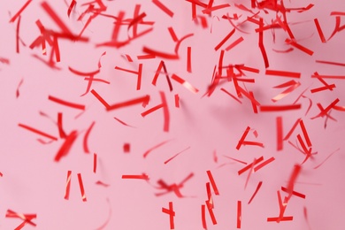 Photo of Shiny red confetti falling down on pink background