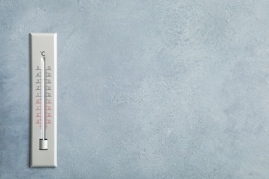 Weather thermometer on grey wall. Space for text