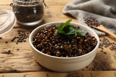 Delicious lentils with parsley in bowl on wooden table, closeup
