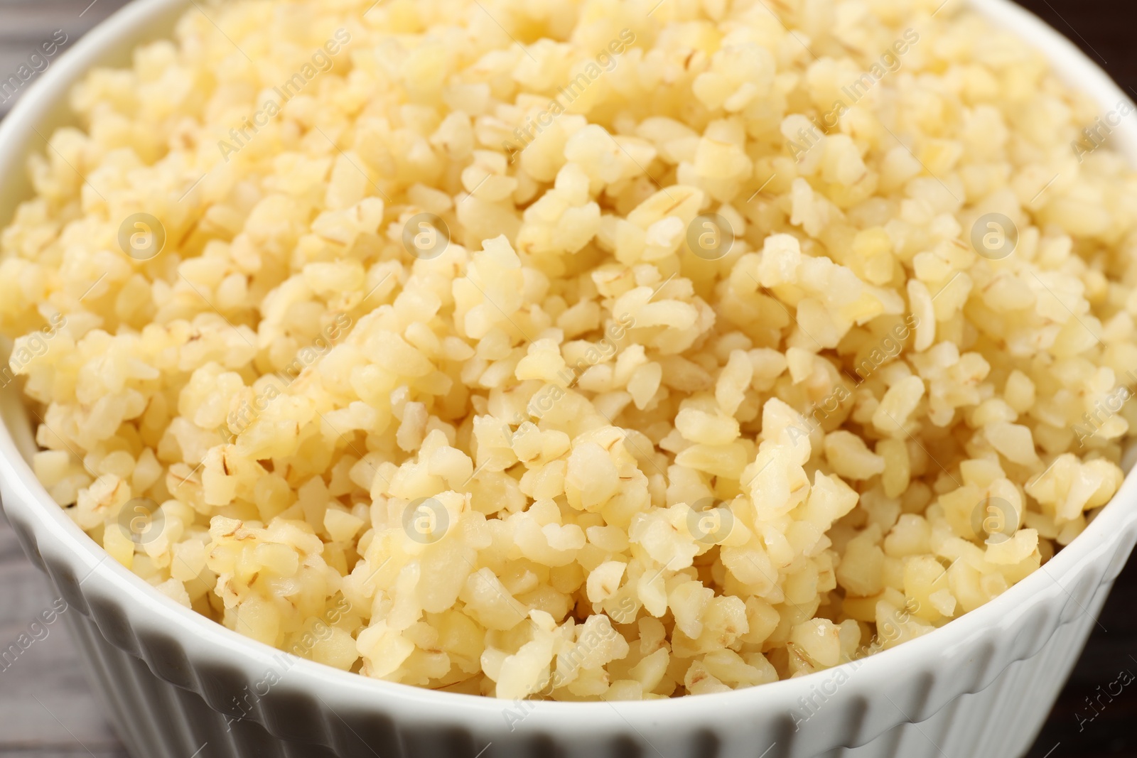 Photo of Delicious bulgur in white bowl, closeup view