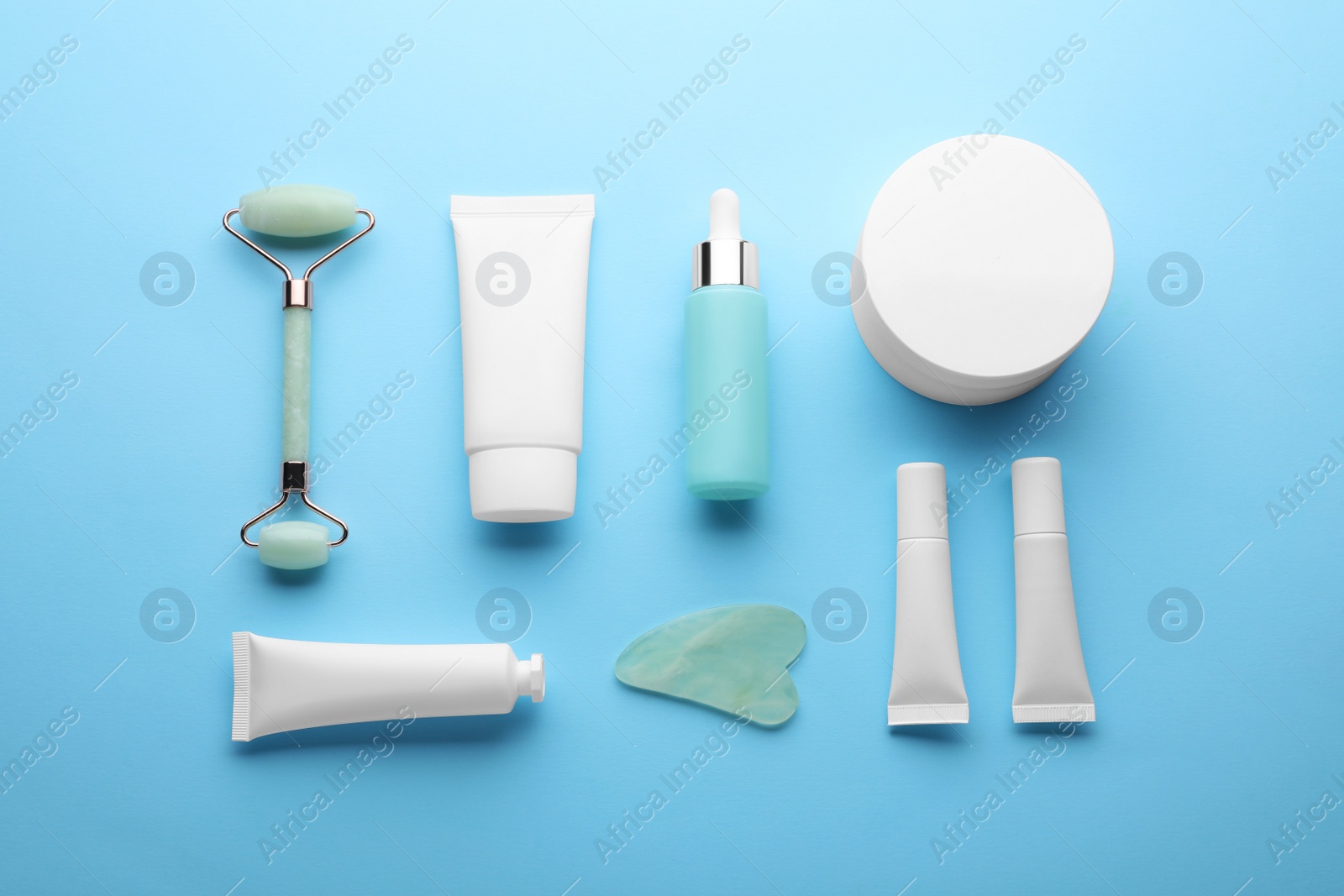 Photo of Natural face roller, gua sha tool and cosmetic products on light blue background, flat lay