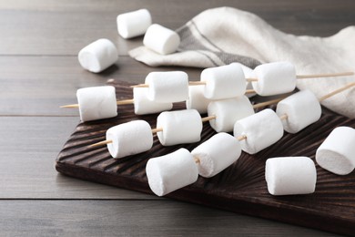 Photo of Sticks with sweet marshmallows on wooden table