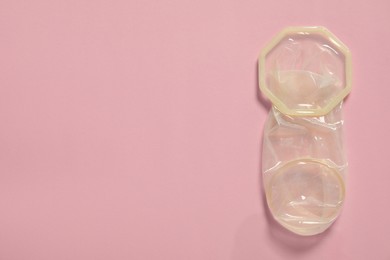 Unrolled female condom on light pink background, top view and space for text. Safe sex