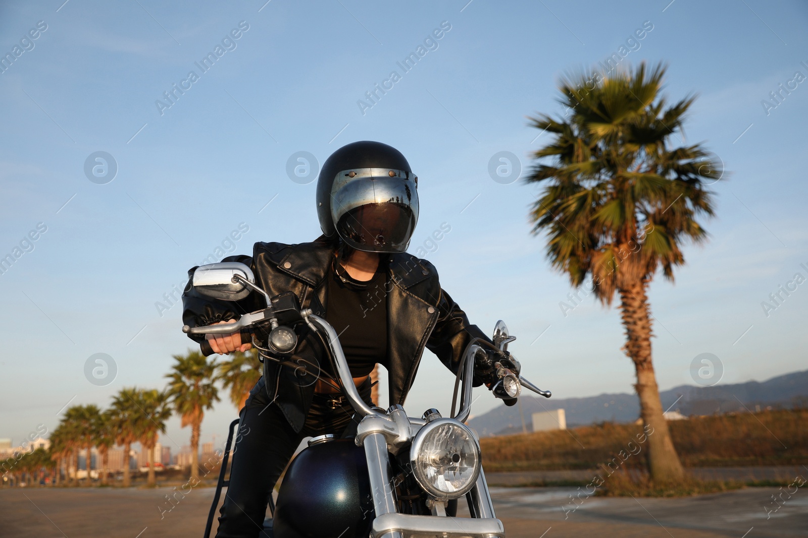 Photo of Young woman in helmet riding motorcycle on sunny day