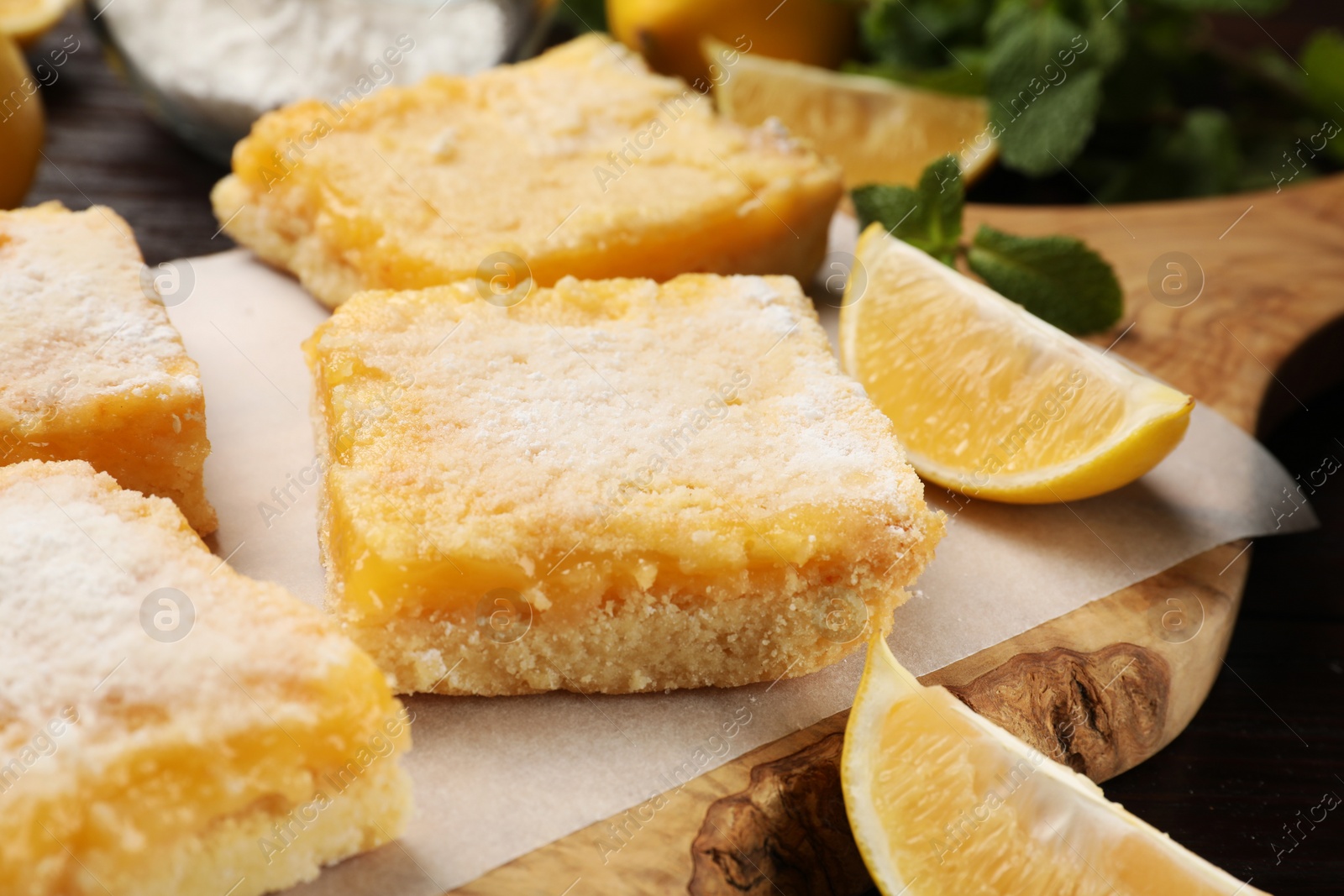 Photo of Tasty lemon bars with powdered sugar on table, closeup