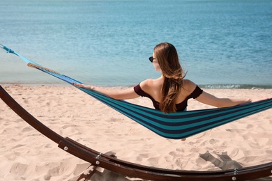 Young woman relaxing in hammock on beach