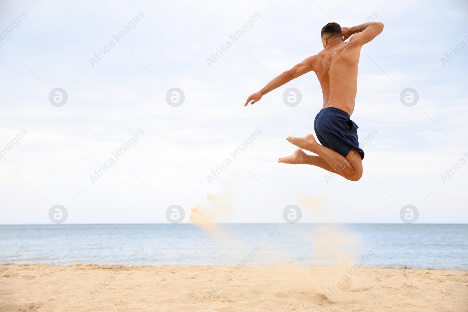 Photo of Muscular man jumping on beach, space for text. Body training