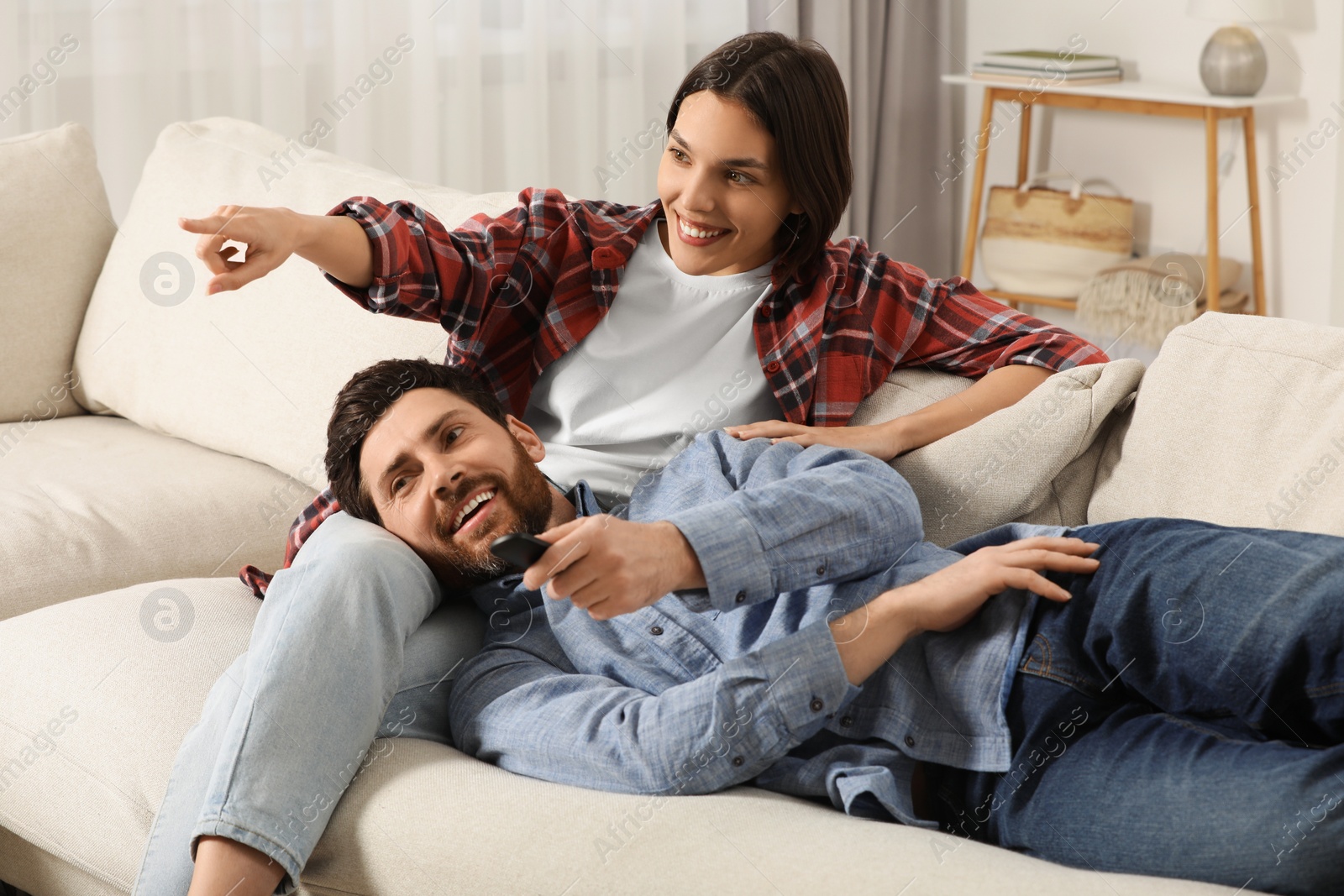 Photo of Happy couple watching TV on sofa at home