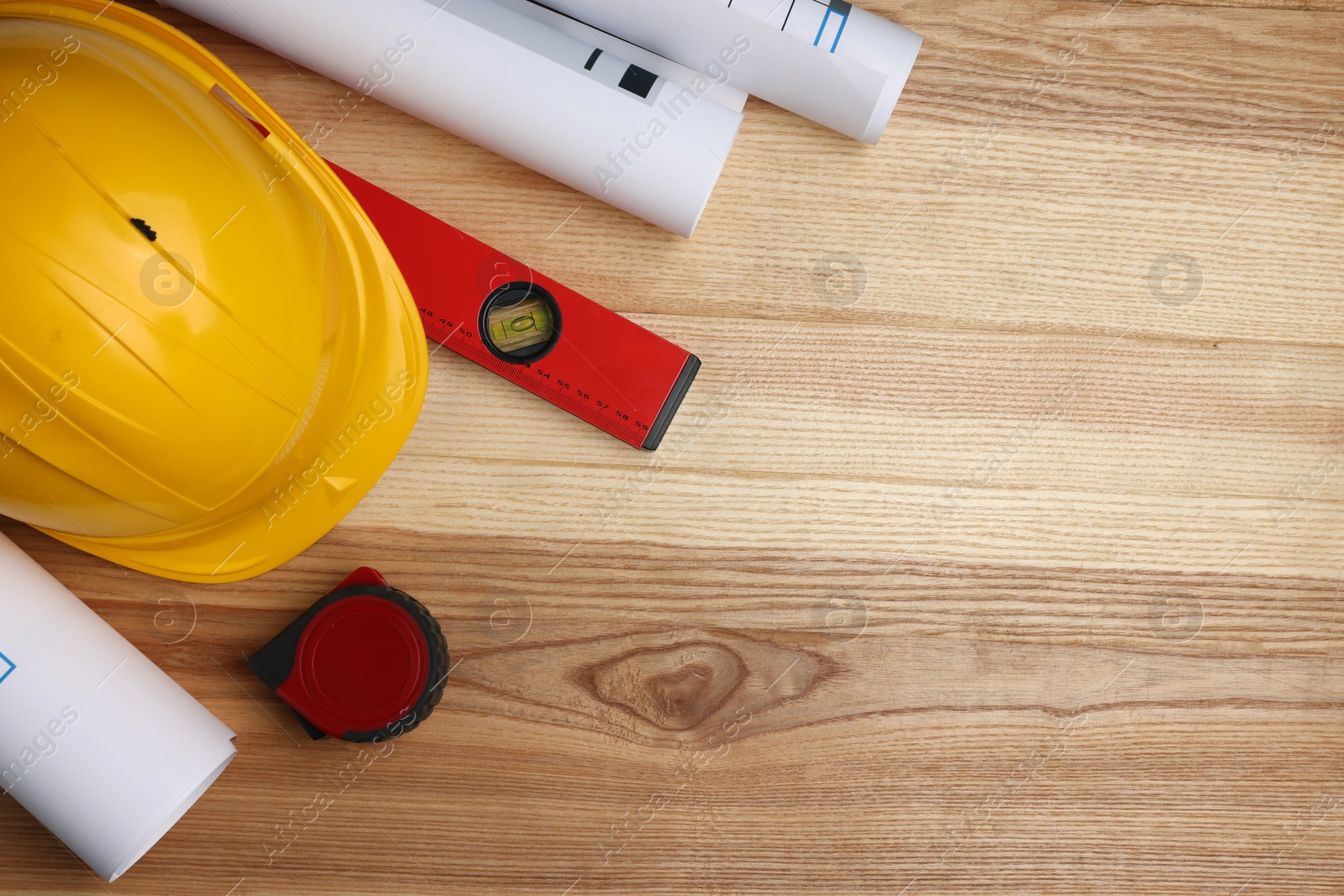 Photo of Construction drawings, safety hat, tape measure and bubble level on wooden table, flat lay. Space for text