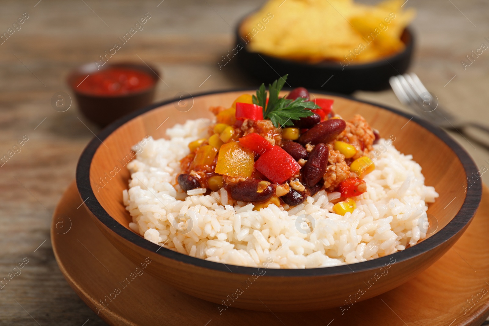 Photo of Chili con carne served with rice in bowl on table