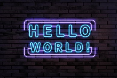 Stylish neon sign with phrase Hello World on brick wall