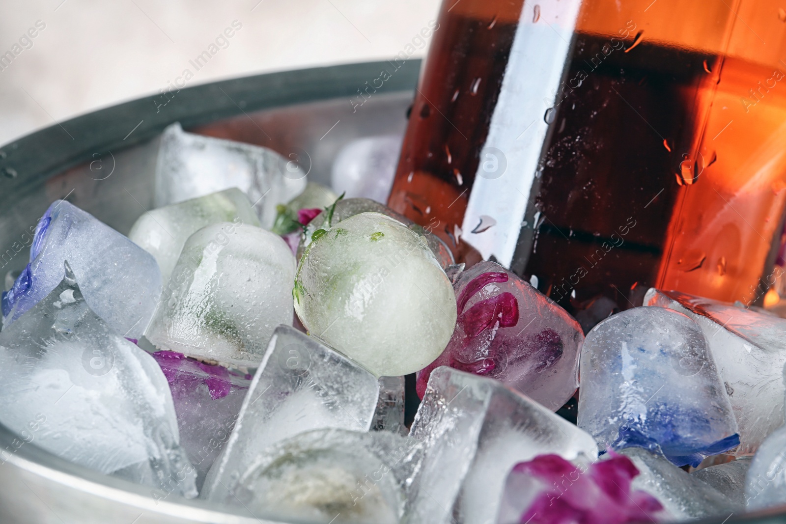 Photo of Floral ice cubes and bottle of champagne in bucket, closeup